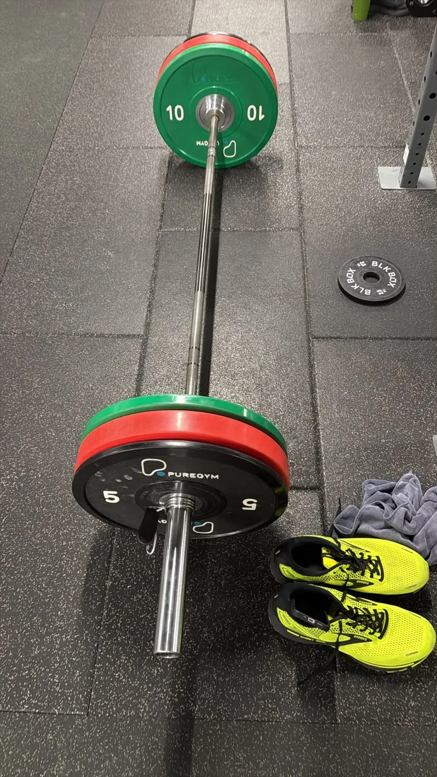 Loaded barbell beside running shoes