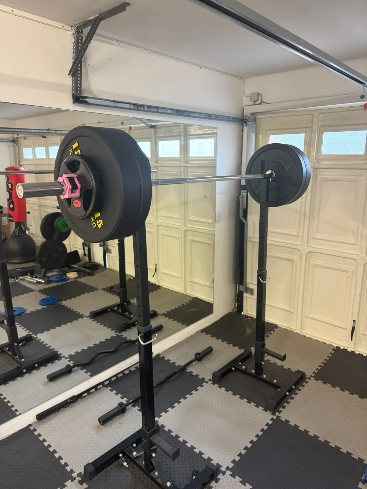 Loaded barbell on squat stands in a home gym